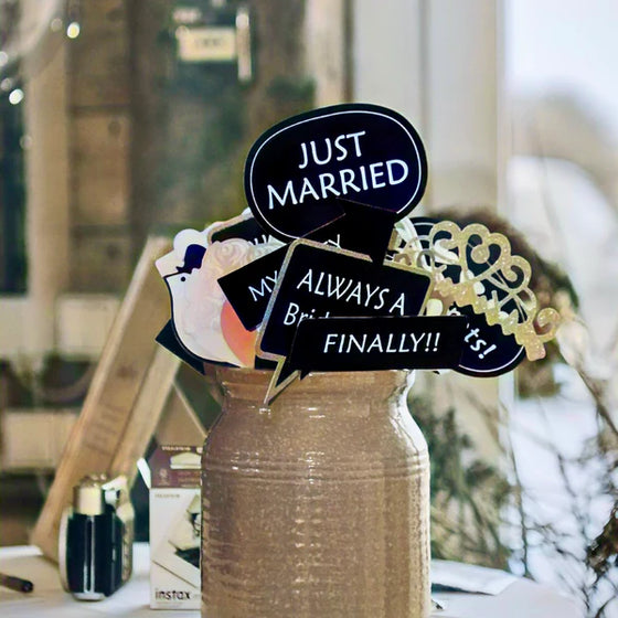 Bröllopsrekvisita med skyltar som Just Married i en kruka på ett bord