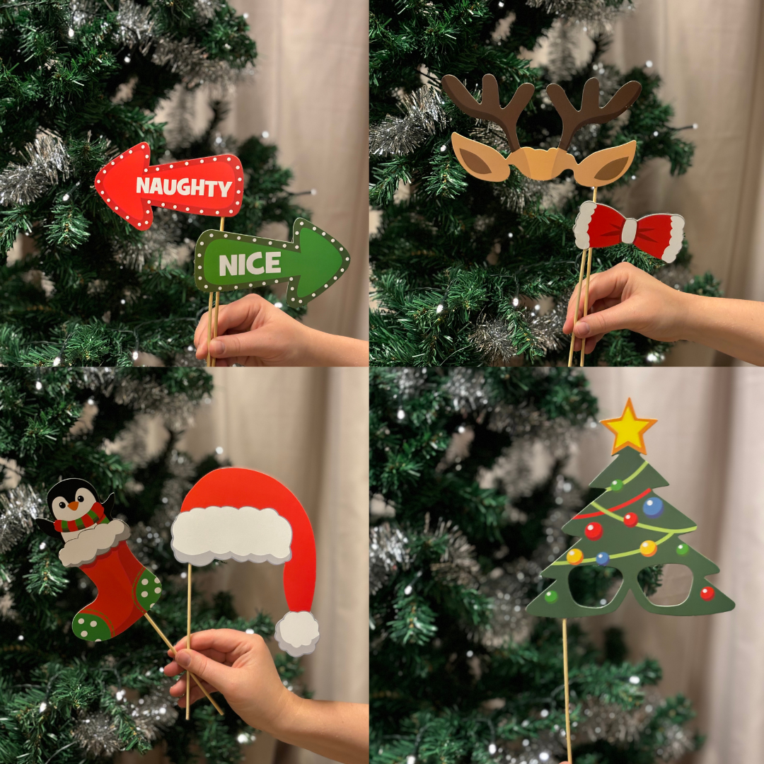 Julrekvisita på pinnar framför en julgran, bland annat tomteluva och renhorn